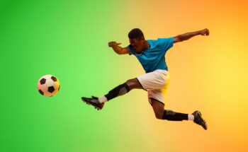 Male-soccer-football-player-training-in-action-isolated-on-gradient-studio-in-neon-light