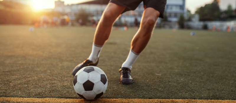 Close em pernas de jogador de futebol com a bola