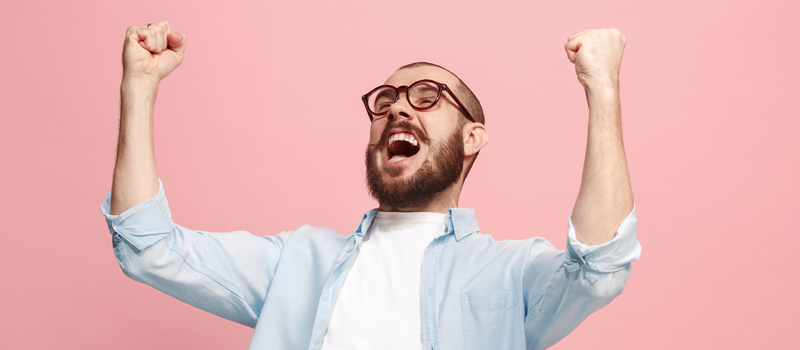 Homem de óculos comemorando em background rosa