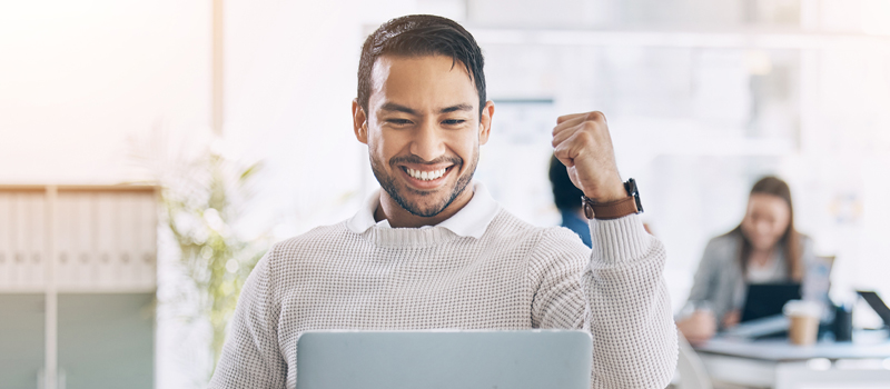 Homem olhando para o computador e comemorando